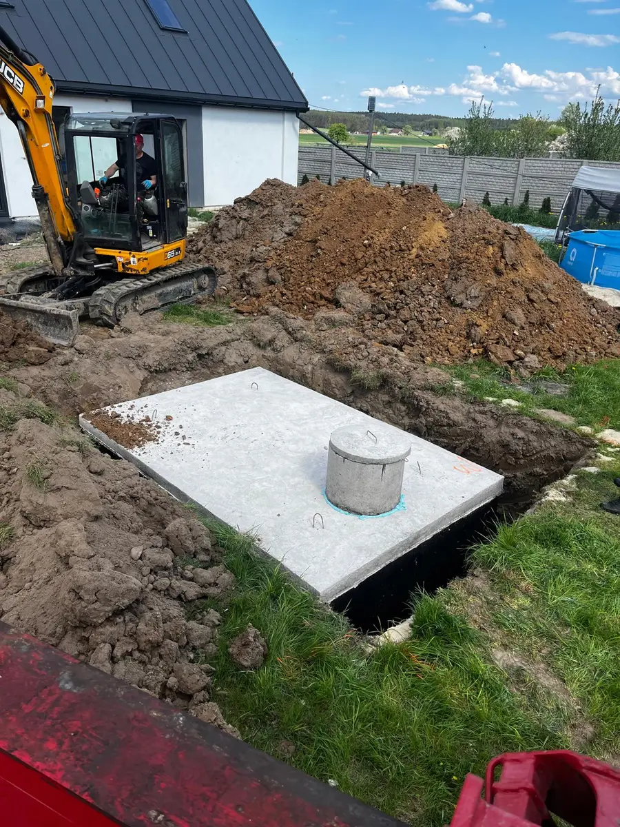 Szambo betonowe przy nowym domu z garażem - koparka JCB