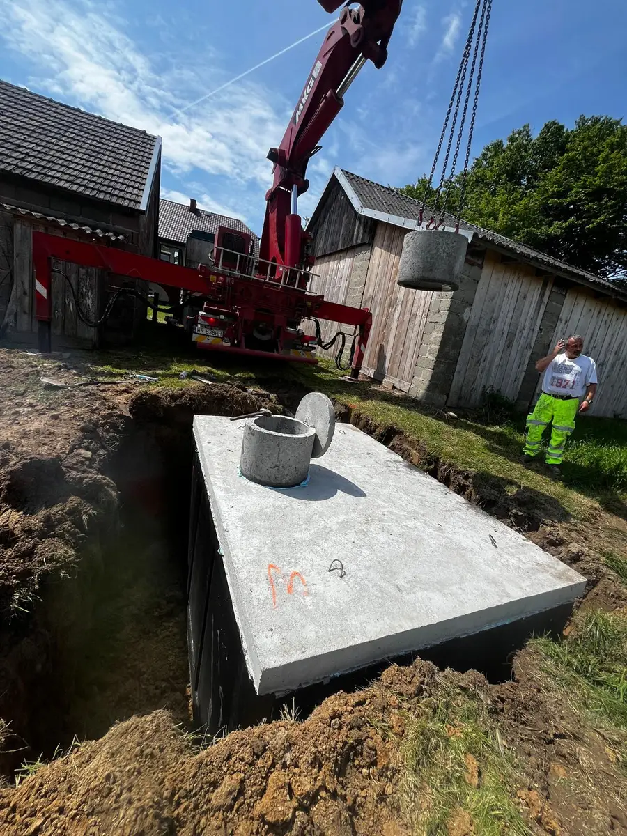 Posadowienie szamba betonowego - czerwony żuraw HDS przy wsi