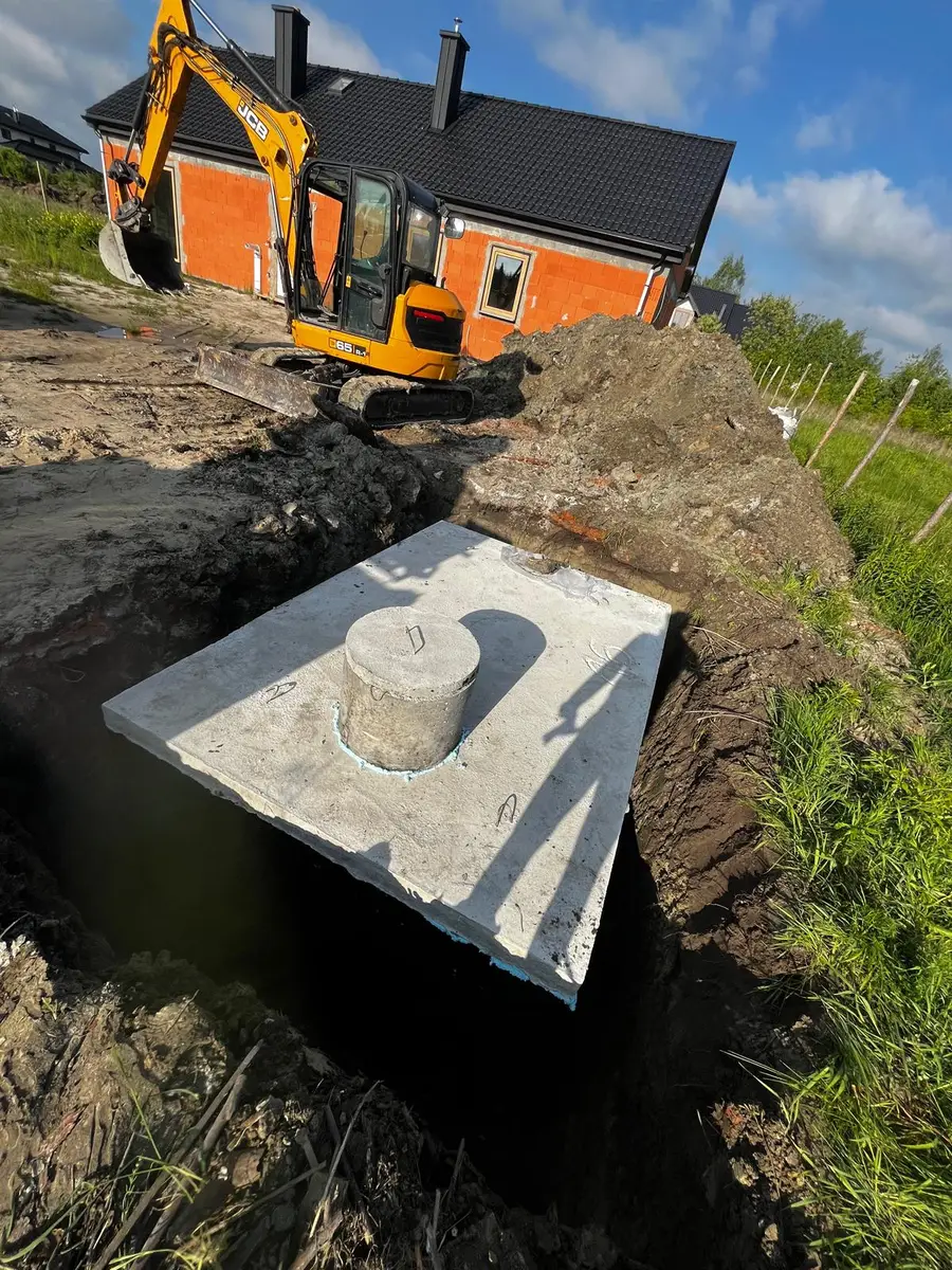 Szambo betonowe posadowione przy domu w budowie - JCB